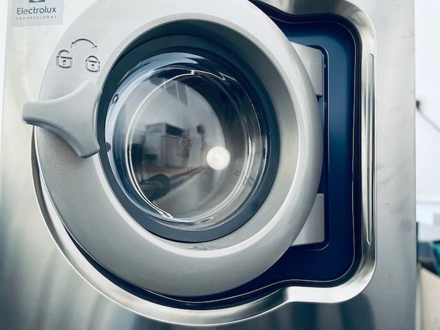 Nahaufnahme einer Electrolux-Waschmaschinentür aus Stahl, die das schlanke Design und das transparente Glasfenster zeigt.